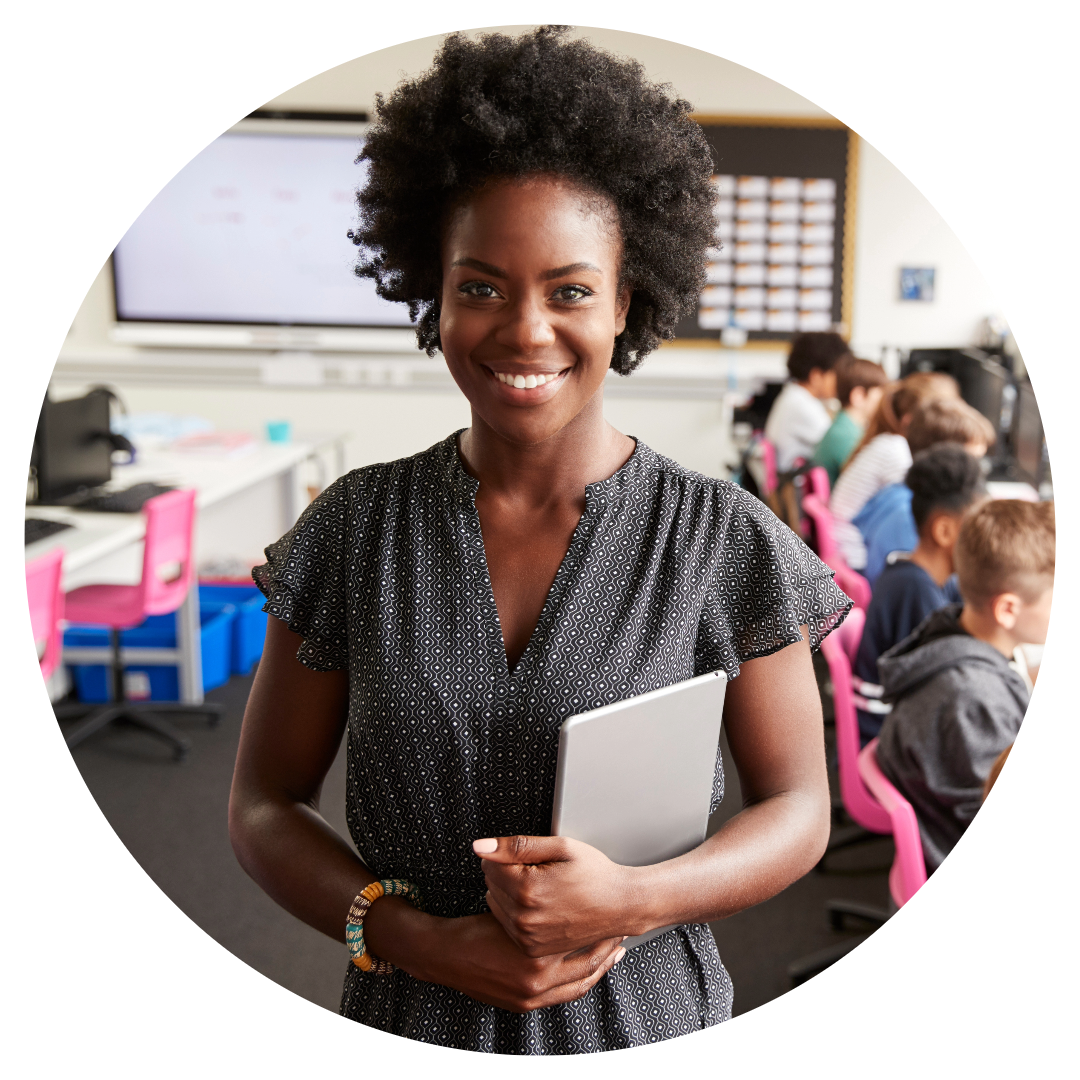 A woman holding a laptop in front of a classroom.