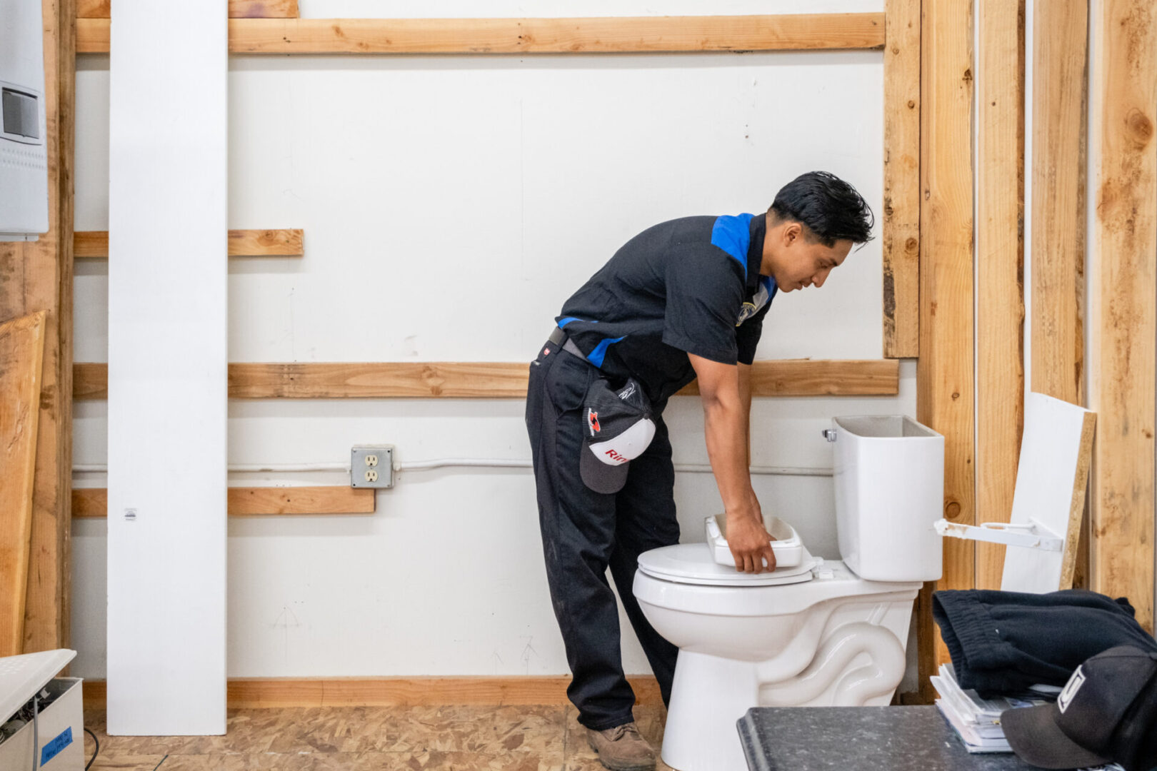 Man fixing toilet in a bathroom.