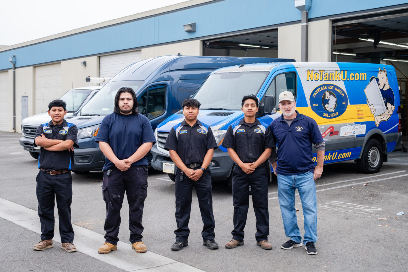 Five men stand in front of vans.