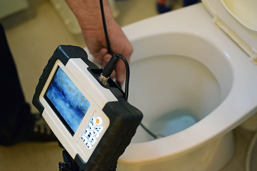 Inspecting toilet drain with a camera.