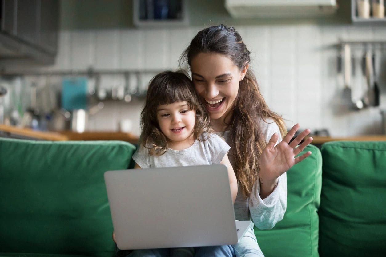 Woman and child smiling at laptop screen.