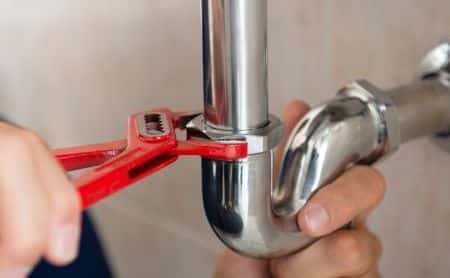 Closeup Of Plumber Fixing Pipe With Wrench